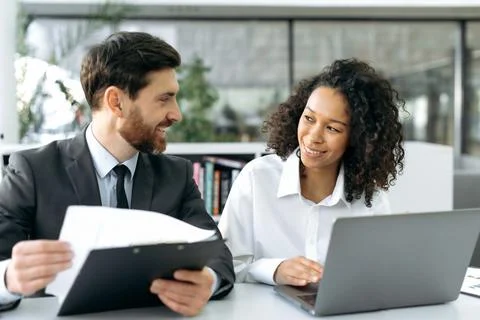 Two successful multi-ethnic colleagues are working together on a project Stock Photos