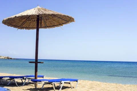 Two sun beds under sun umbrella at the beach. Zephyros beach. Greece Stock Photos