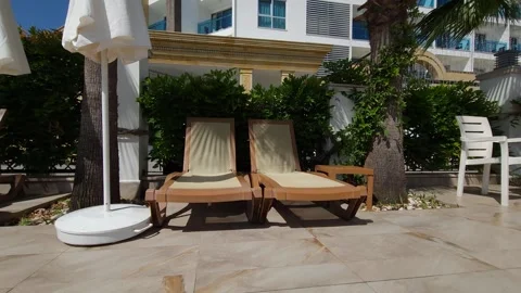 Two sun loungers bask in the shadow of palm branches creating a serene scene Stock Footage 277182126