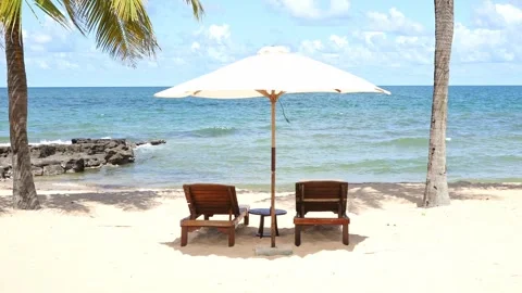 Two sun loungers bed under an umbrella on sandy beach. Summer all year round Stock Footage 312815253