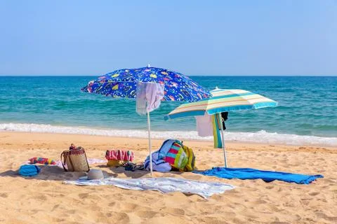 Two sun umbrellas and beach supplies at sea Stock Photos