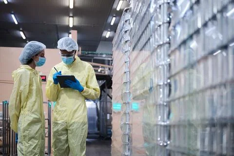 Two supervisors inspect quality of containers in canned food manufacturing. Stock Photos