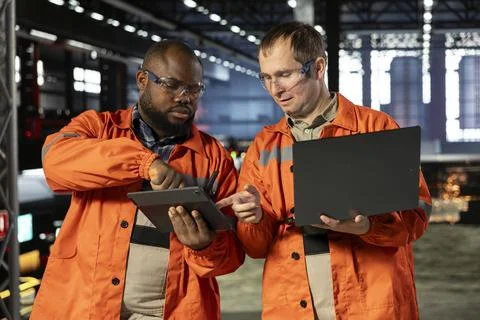 Two supervisors using laptop and tablet to guide personnel during fabrication Stock Photos