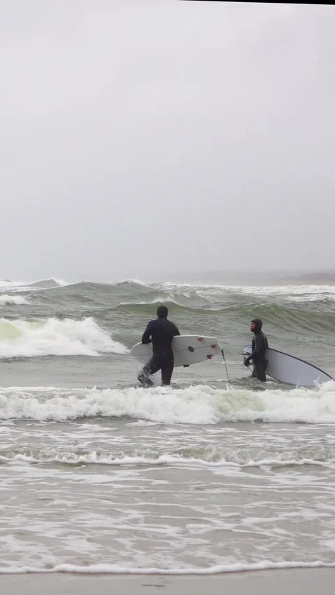 Two surfer in wetsuit trying to catch a wave in a cold stormy sea on a windy day 스톡 동영상 311704138