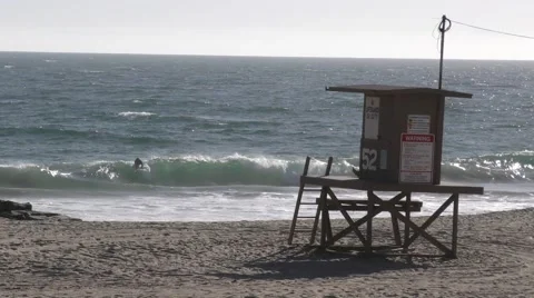 Two surfers catching waves by a life guard stand on a windy beach day Video stock 67616266