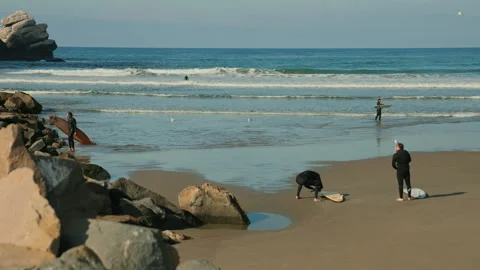 Two surfers entering the waters for wave surfing at the Morro Bay beach Stock Footage 346921958