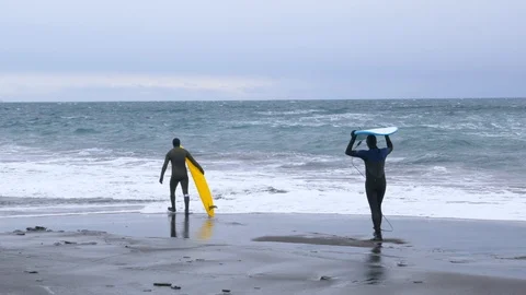 Two surfers go to the ocean in winter 007 Stock Footage 124768828