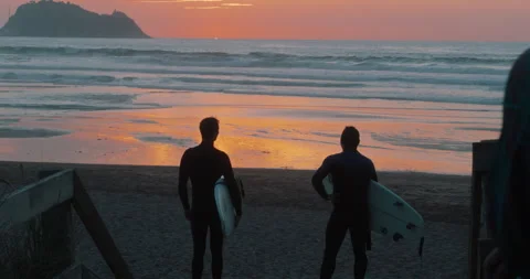 Two surfers look at waves at sunset at epic beach Stock Footage 277220703