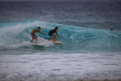 Two surfers on the same wave Stock Photos