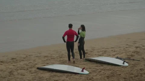 Two Surfers Standing on Sandy Beach with Surfboards in Gijon, Asturias, Spain Видео 335898094