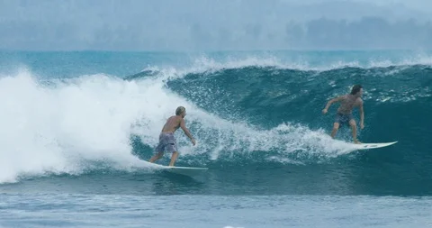 Two surfers surfing on a big wave in turquoise sea in slow motion Stock Footage 85765052
