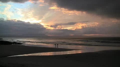 Two surfers walk along beach at sunset. Australia Stock Footage 11348451