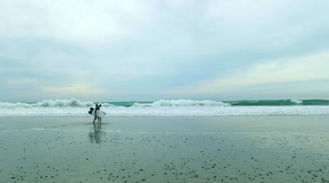 Two surfers walk on a calm beach with surfboards UHD 4K Stock Footage 56445663