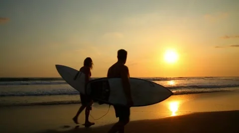 Two surfers walk at sunset on the beach Stock-Footage 42305120