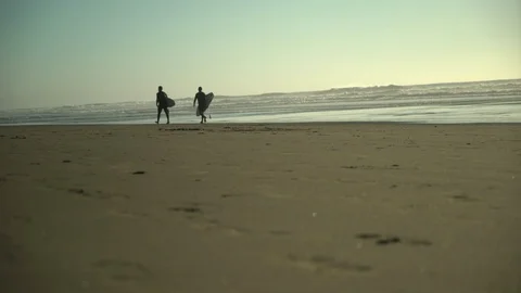 Two surfers walking along beach Stock Footage 125787216