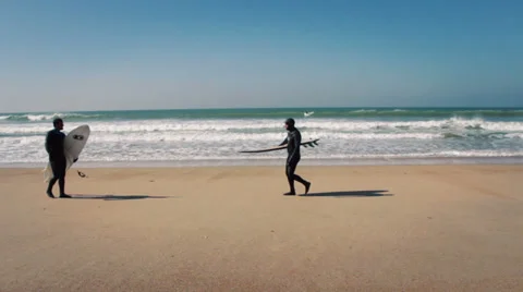 Two surfers walking on the beach Stock Footage 35950700