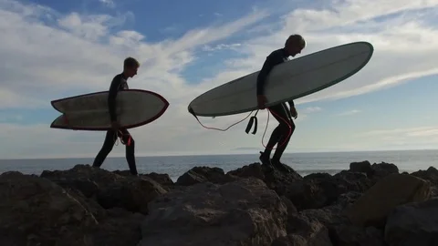 Two Surfers Walking on Beach Rocks 库存影片 72583191