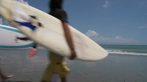 Two surfers walking from off camera crossing the beach  to reach the ocean Stock Footage 559586