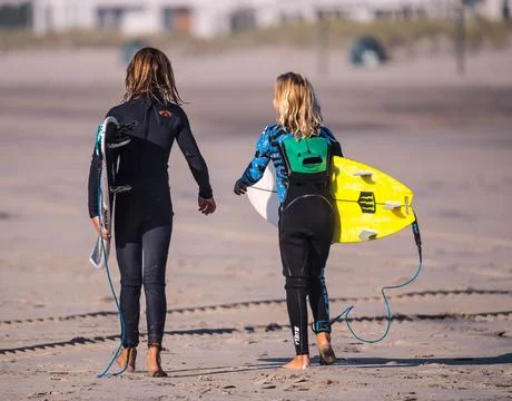 Two Surfers Walking down beach holding their surf boards Stock Photos