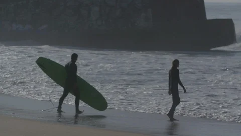 Two surfers walking to the waves with a surfboard - Slow motion Stock Footage 105311414