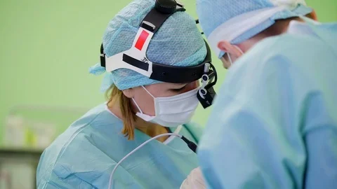 Two surgeons are wearing protective uniforms and masks are performing operation 스톡 동영상 97002378