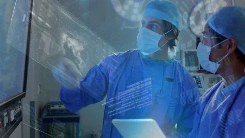 Two surgeons consulting in OR, right surgeon tapping tablet showing data Stock Footage 334768374