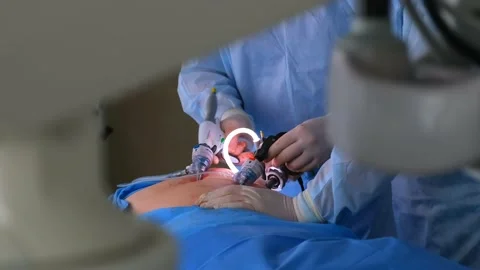 Two surgeons in lab coats and an assistant perform endoscopic surgery Stock Footage 132735754