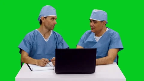 Two surgeons looking at laptop and discussing something on green screen Video stock 126341062