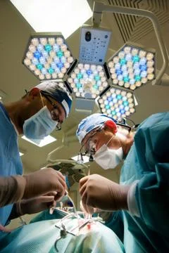 Two surgeons in operating room making plastic surgery. Stock Photos