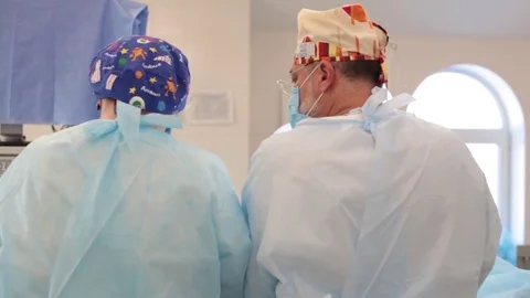 Two surgeons in the operating room. stand with his back to the camera and bent o Stock Footage 70809480