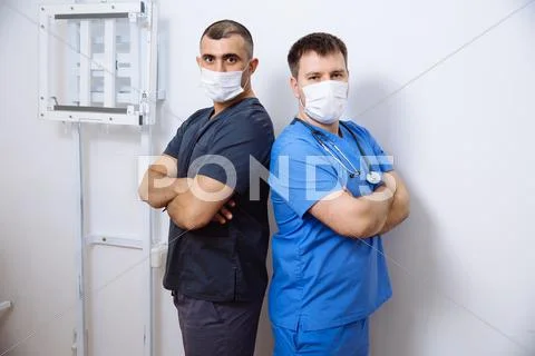 Two surgeons in sterile uniforms standing back to with arms folded and looking Stock Photos