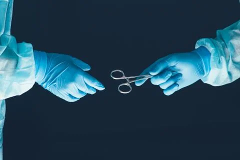 Two surgeons working and passing surgical equipment in the operating room Stock Photos