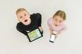 The two surprised children stand with devices. View from above Photo