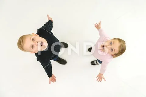 The two surprised children stand on the white background. View from above Stock Photos