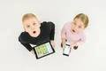 The two surprised kids stand with devices. View from above Photo
