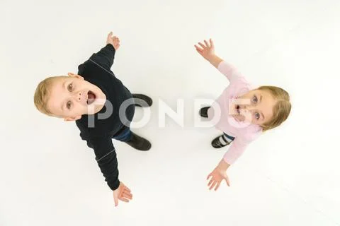 The two surprised kids stand on the white background. View from above Stock Photos
