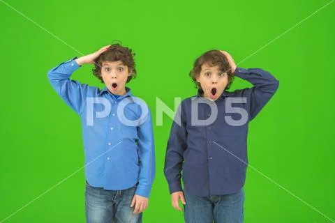 The two surprised twin kids gesture on the green background Stock Photos