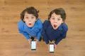 The two surprised twin stand with a phone. View from above Photo