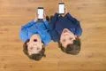 The two surprised twin stand with a phone. View from above Photo