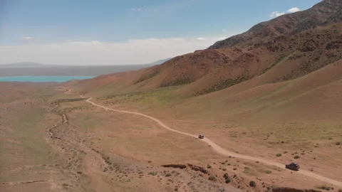 Two SUVs are driving along the gorge in the direction of a mountain lake. Stock Footage 208860301