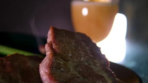 Two sweaty cold tulipa glasses of beer with grilled sliced cap rump steak on Vídeos de archivo 294527119