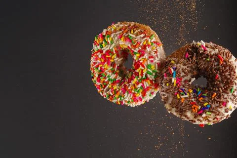 Two sweet donuts decorated with multi-colored confectionery sprinkles on a gr Stock Photos
