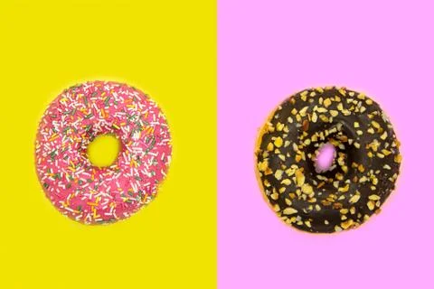 Two sweet glazed donuts top view: strawberry with with sprinkles on yellow an Stock Photos
