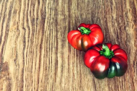 Two sweet red peppers on rustic wooden background.Toned image. Stock Photos