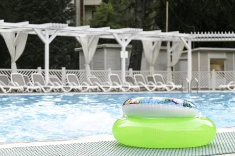Two swimming circles lie by the pool with blue water on summer day. Stock Photos