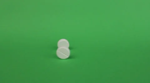 Two tablets rolling out in the frame and then one rolling back, green background Video stock 25877437