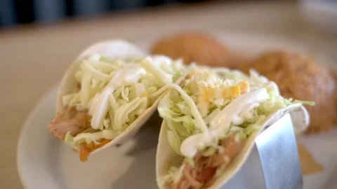 Two tacos filled with shredded lettuce and cheese, topped with a drizzle of s Video stock 275877111