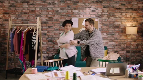 Two tailors are ecstatic to work together as they are dancing around to the Stock Footage 194279700