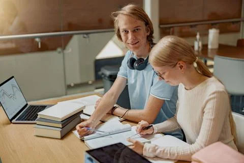 Two talented students working together on university project sitting in library Stock Photos
