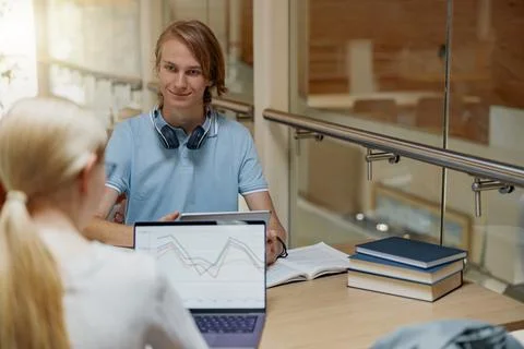 Two talented students working together on university project sitting in library Stock Photos
